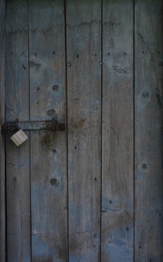 Kilitli ve kapının mandalı olan eski mavi ahşap kapı. Kapıyı kapat.