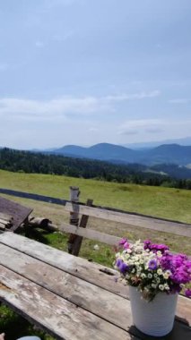 Tahta bir masada yabani çiçekler. Dağların manzarası