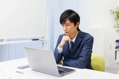 Modern ofiste bilgisayar üzerinde çalışan yakışıklı Japon işadamı. 