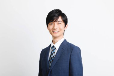 Ofisteki genç Japon adam ayakta kameraya bakıyor.