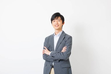 Ofisteki genç Japon adam ayakta kameraya bakıyor.