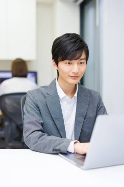 Ofiste dizüstü bilgisayarla çalışan mutlu bir Japon 'un portresi..