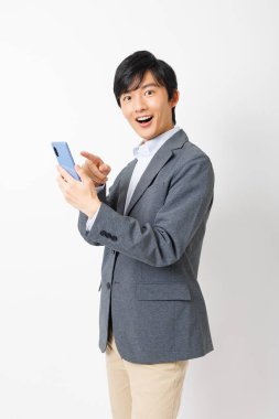 Genç bir Japon beyaz arka planda akıllı telefon kullanıyor.