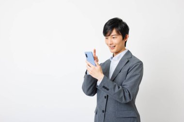 Genç bir Japon beyaz arka planda akıllı telefon kullanıyor.