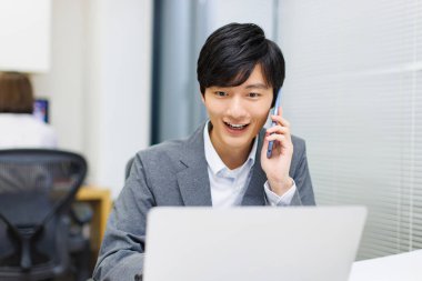 Ofiste dizüstü bilgisayarla çalışan mutlu bir Japon 'un portresi..