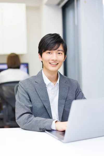 一个英俊的日本男人在办公室的笔记本电脑上工作 — 图库照片