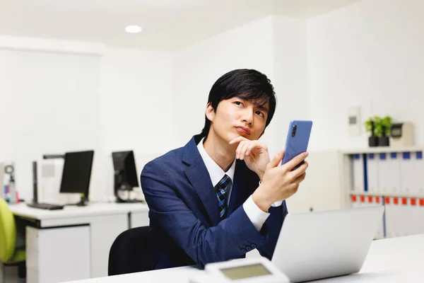 Νεαρός Ιάπωνας Επιχειρηματίας Που Χρησιμοποιεί Τηλέφωνό Του Στο Γραφείο — Φωτογραφία Αρχείου