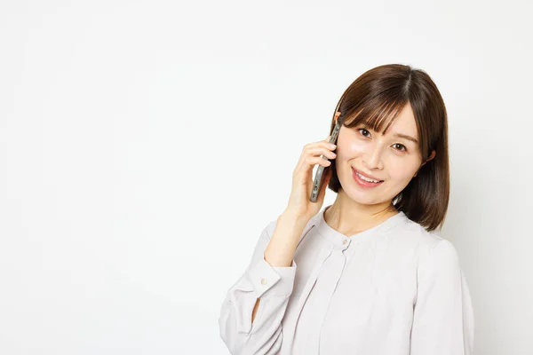 在办公室里的年轻日本女人穿上衣服在电话里聊天 — 图库照片