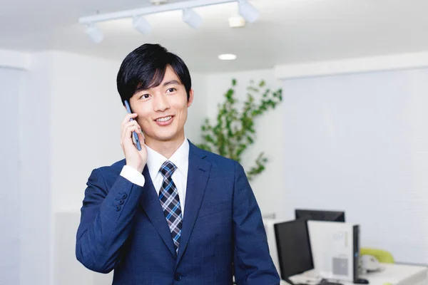 年轻的日本商人在办公室工作时通过电话交谈 — 图库照片