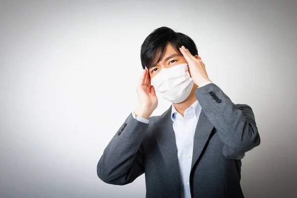 ハンサムな日本人ビジネスマンとフェイスマスク感じの頭痛 — ストック写真