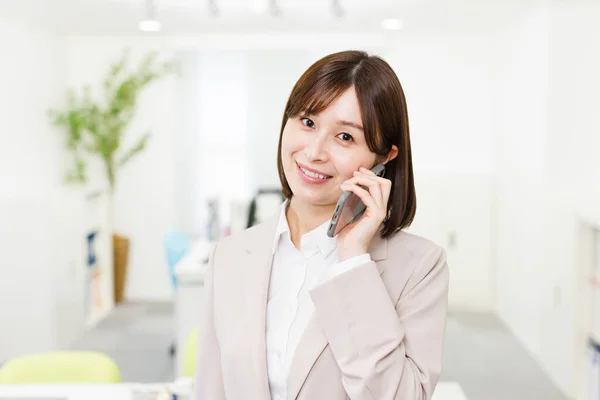 在办公室里的年轻日本女人穿上衣服在电话里聊天 — 图库照片