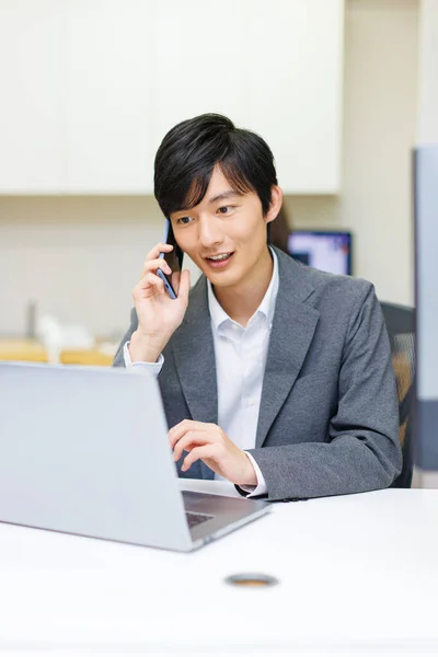 年轻的日本商人在办公室工作时通过电话交谈 — 图库照片