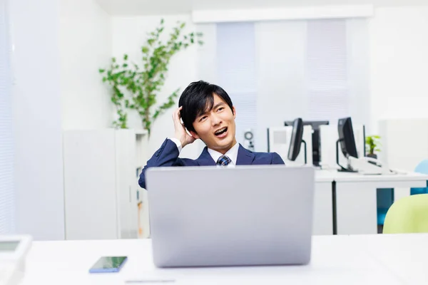 Young Japanese businessman feeling frustrated in the office