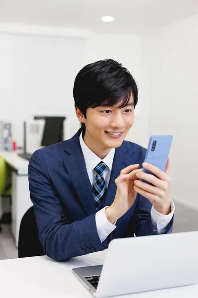 オフィスで携帯電話を使っている若い日本人男性 — ストック写真