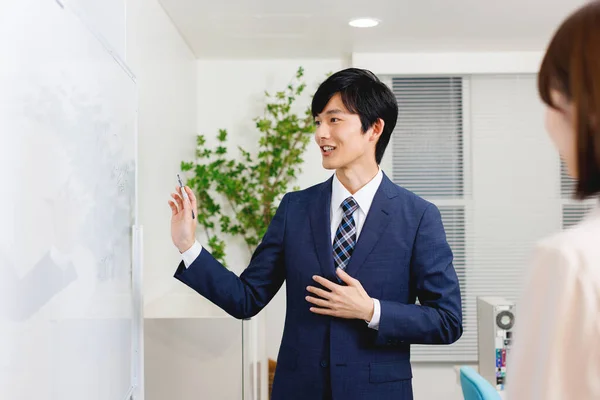 Νεαρός Ιάπωνας Στο Γραφείο Ντύνεται Παρουσιάζοντας Επιχειρηματικό Σχέδιο Στη Συνάδελφό — Φωτογραφία Αρχείου