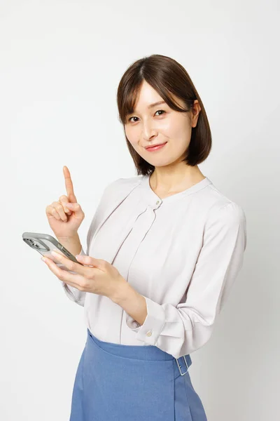 Młoda Japonka Stroju Biurowym Pokazuje Gest Podczas Korzystania Smartfona — Zdjęcie stockowe