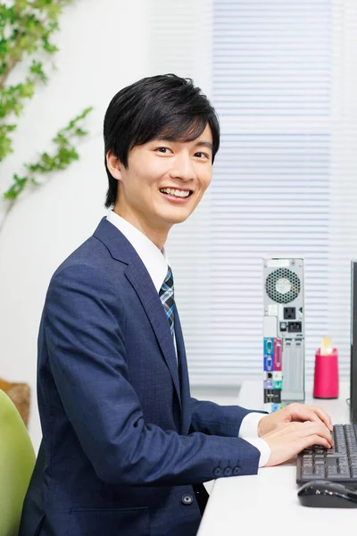 一个英俊的日本商人在现代办公室的电脑上工作 — 图库照片