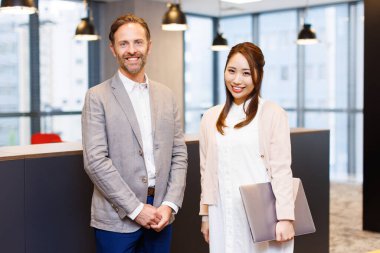 Yakışıklı beyaz adam ve güzel Japon kadın modern ofiste birlikte çalışıyorlar.