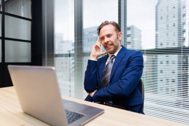 Modern ofiste çalışan mavi takım elbiseli yakışıklı beyaz adam.