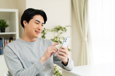 Evde cep telefonu kullanan bir Japon.