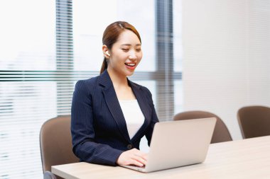 Modern ofis binasında dizüstü bilgisayarda çalışan güzel bir Japon kadın.