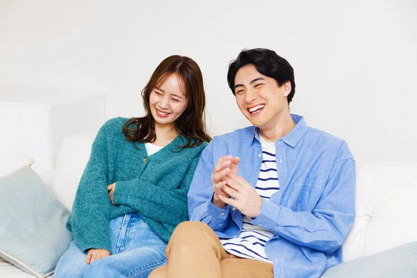 young asian couple sitting at couch with television