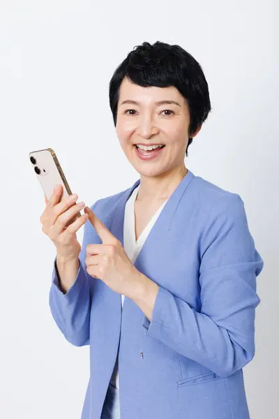 Pozytywny Średnim Wieku Japońska Kobieta Niebieskiej Kurtce Pomocą Smartfona Białym — Zdjęcie stockowe