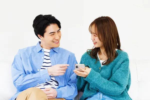 Joven Pareja Japonesa Sentada Sofá Casa Utilizando Teléfono Inteligente — Foto de Stock