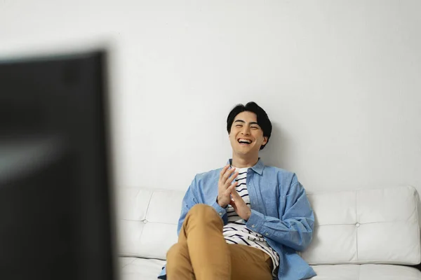 asian young man watching tv at home