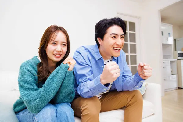 Glada Unga Asiatiska Par Tittar Soffan Vardagsrummet — Stockfoto