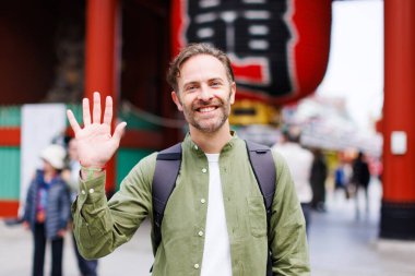 Sırt çantalı beyaz adam Japon kültürünü keşfediyor. 