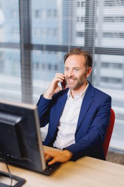 Modern ofisteki yakışıklı beyaz adam telefonda konuşuyor.