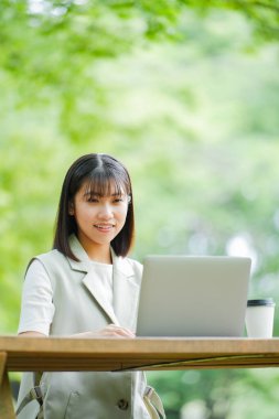 Yaz parkında dizüstü bilgisayarda çalışan Asyalı kadın.