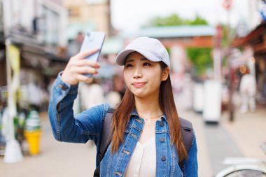 Japon kadın sokakta selfie çekiyor. Şehirde fotoğraf çeken çekici bir bayan turist. 