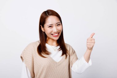 Beyaz arka planda baş parmağını gösteren güzel Japon kadının stüdyo portresi. 