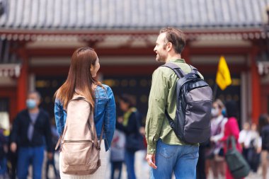 Beyaz adam ve Japon kadın Japon tapınağını geziyorlar.