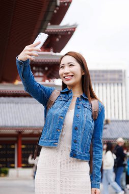 Japon kadın sokakta selfie çekiyor. Şehirde fotoğraf çeken çekici bir bayan turist. 
