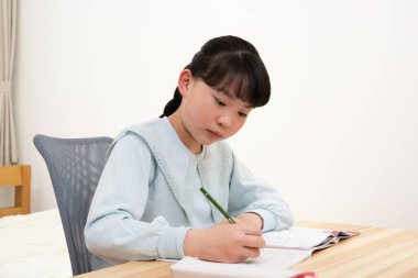 Not defterine yazan Asyalı küçük kız.