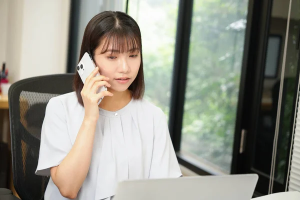 Beautiful Japanese woman talking on the phone in the modern office