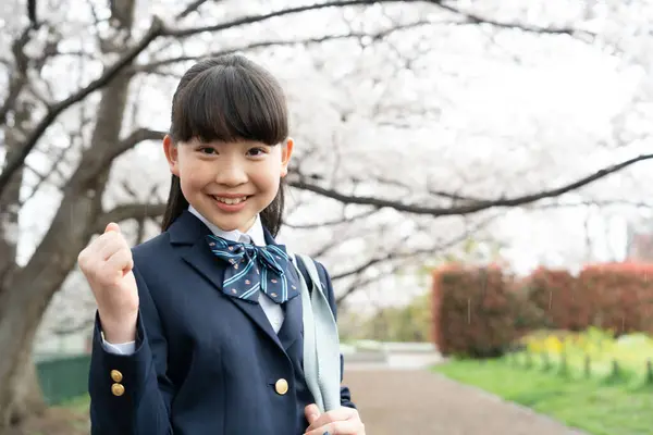 公園の背景に桜が咲いているアジアの女子生徒 — ストック写真