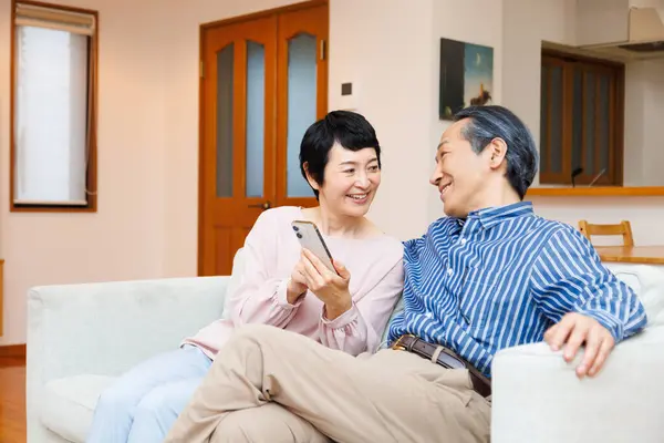 Asyalı Olgun Çift Evde Akıllı Telefon Kullanıyor — Stok fotoğraf