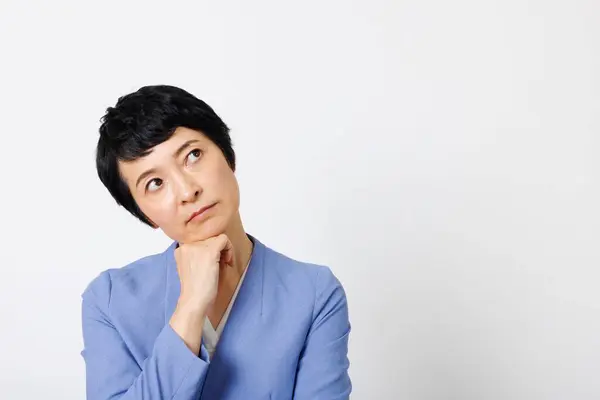 Mavi Ceketli Japon Kadının Beyaz Arka Planda Bir Şeyler Düşünen — Stok fotoğraf