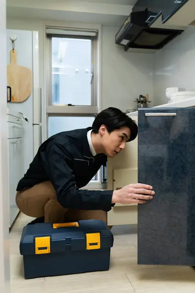asian man plumber working at kitchen