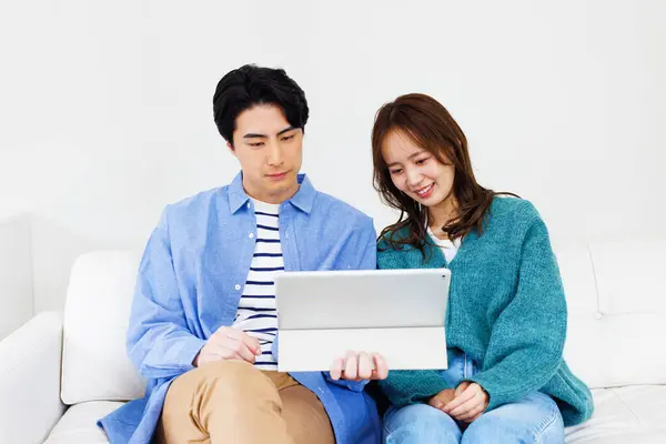 Genç Japon Çift Evdeki Kanepede Oturup Dijital Tablet Kullanıyorlar — Stok fotoğraf