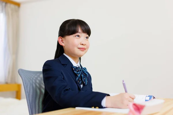 穿着校服做作业的可爱的日本女孩的画像 — 图库照片