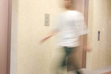 Asyalı bir adamın otelin koridorunda yürürken görüntüsü bulanık.