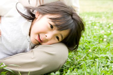 Küçük Asyalı kız annesinin kucağında yatıyor.