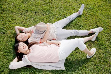 Genç Japon kadınları gündüz vakti çimenlerde yatıyorlar.  