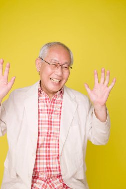 Sarı arka plandaki kıdemli Asyalı adam..