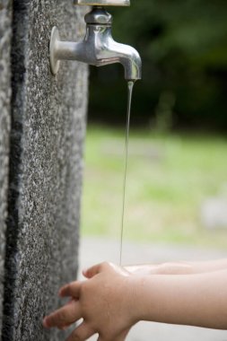 Bahçede ellerini yıkayan çocuk, kesilmiş fotoğraf.